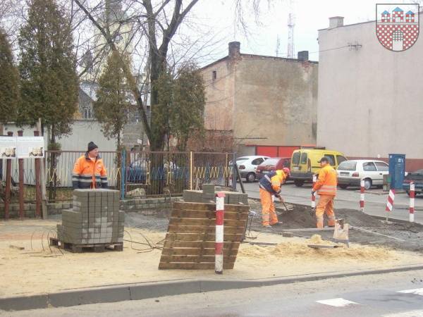 : Pracownicy w trakcie układania kostki brukowej na nowy chodnik